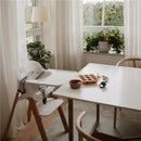 Mushie Baby Food Freezer Tray in blush color on a table, alongside a small bowl and a baby spoon, in a cozy dining space.