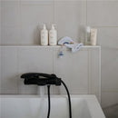 Gray organic cotton bath mitts from Mushie, displayed beside multiple bath products on a bath ledge.