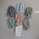 Organic cotton bath mitts in gray, pink, green, and blue colors, arranged neatly, showcasing their soft texture.