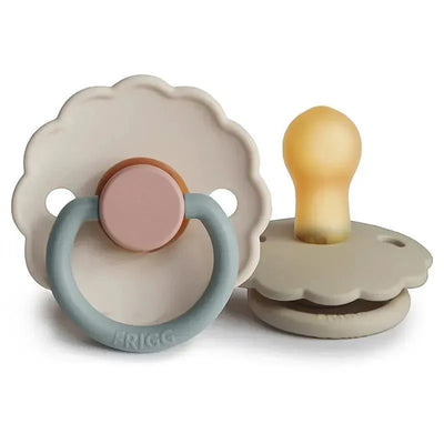 Two Frigg Daisy natural rubber pacifiers in Sandstone and Cotton Candy colors, designed for infants 0-6 months.
