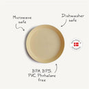 Mushie silicone round plate in powder blue, labeled as dishwasher and microwave safe, BPA-free, with brand logo.