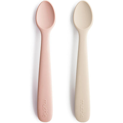 Silicone feeding spoons in blush and shifting sand colors, designed for feeding babies, with soft, rounded edges.
