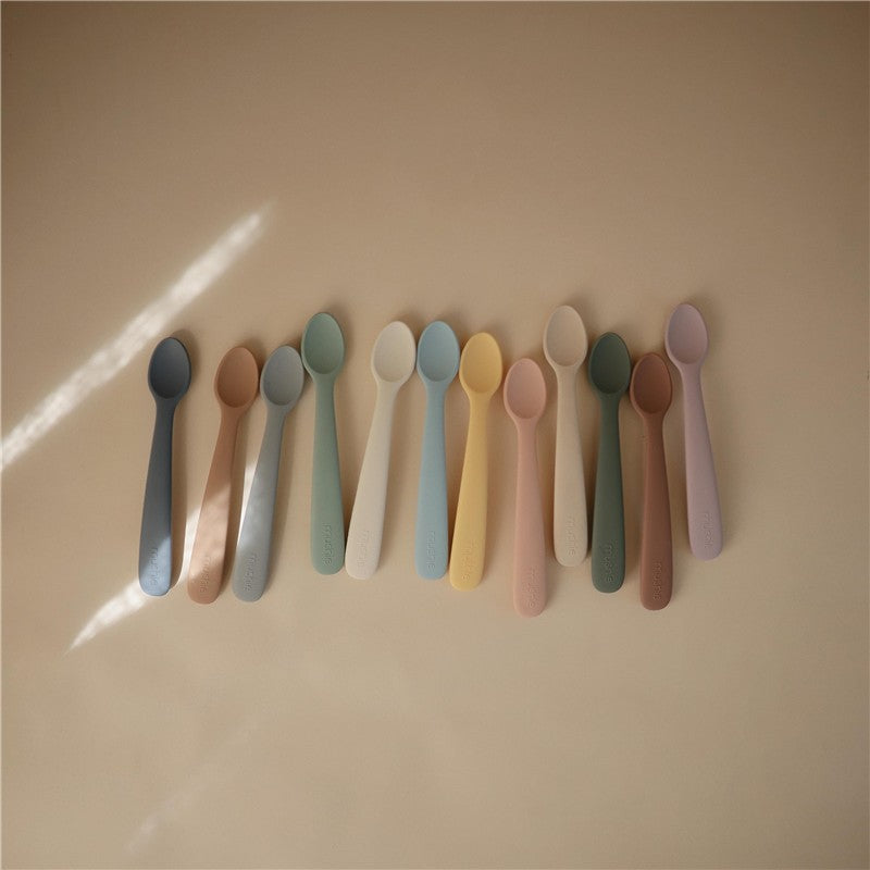 Mushie Silicone Feeding Spoons in blush and shifting sand colors, featuring a variety of soft pastel shades arranged neatly.