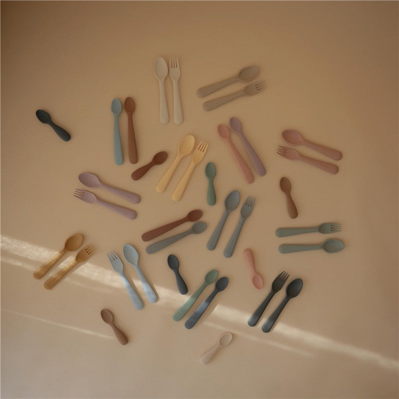 Mushie Silicone Feeding Spoons 2 Pack in Blush and Shifting Sand, featuring various soft-colored spoons and forks.