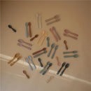Mushie silicone feeding spoons in various colors, including Cambridge Blue and Shifting Sand, displayed on a flat surface.