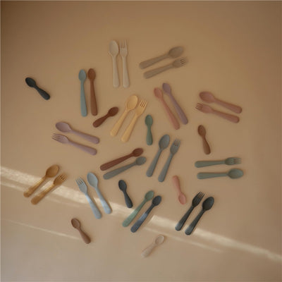 Mushie silicone feeding spoons in diverse colors, arranged on a light background, highlighting their soft, kid-friendly design.