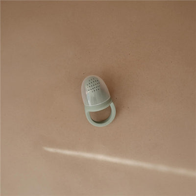 Mushie Silicone Fresh Food Feeder in Cambridge Blue, designed for infants to safely chew on fruits and vegetables.