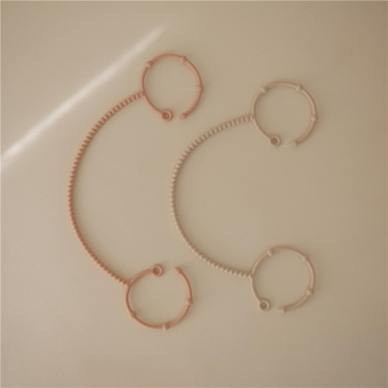 Adjustable silicone straps in blush and shifting sand colors, designed for securing items, displayed flat on a light background.