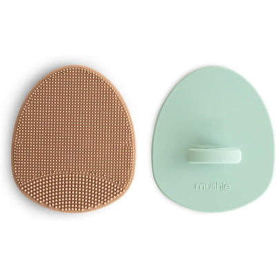 Silicone baby bath cradle cap brush set in natural and Cambridge blue, featuring textured surfaces for gentle cleaning.