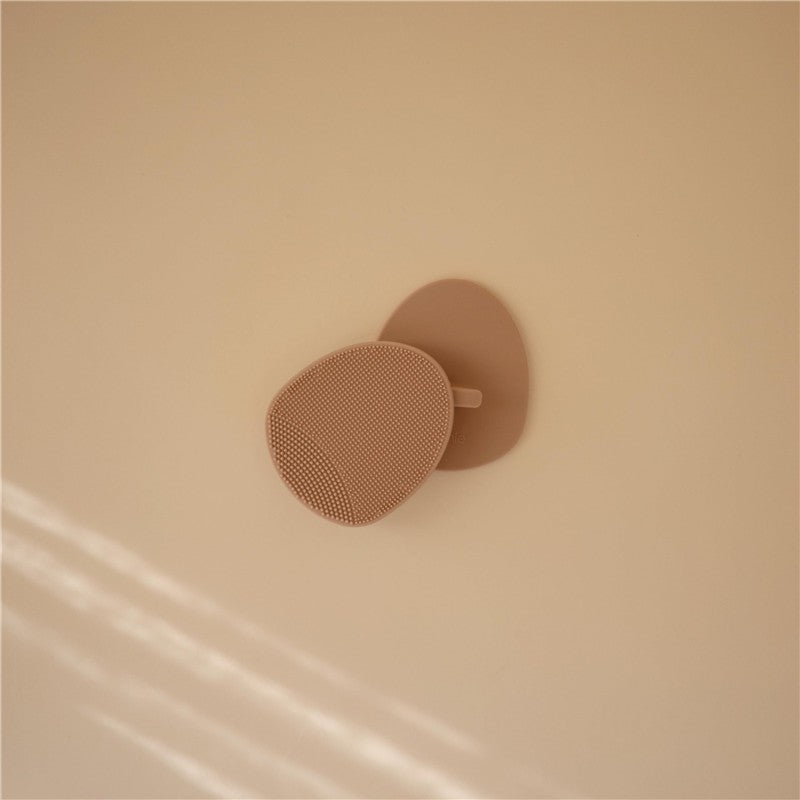 Mushie Silicone Baby Bath Cradle Cap Brush in natural color, featuring a textured surface for gentle cleaning.