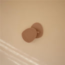 Mushie Silicone Baby Bath Cradle Cap Brush in natural color, featuring a textured surface for gentle cleaning.
