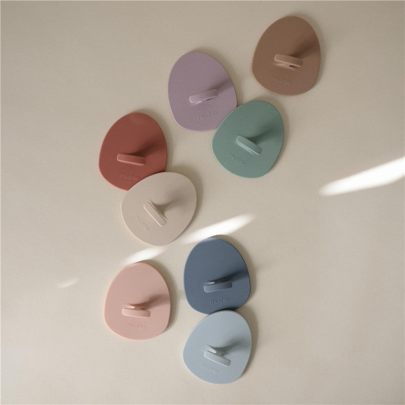 Silicone baby bath cradle cap brushes in various pastel colors arranged on a light background.