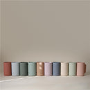 Mushie Bath Rinse Cups in various pastel colors, displayed in a row, showcasing their ribbed texture and handle.