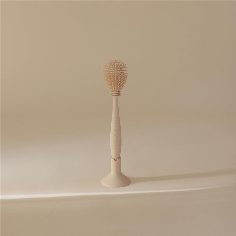 Mushie Silicone Baby Bottle Brush in Shifting Sand color, featuring a durable silicone bristle head and ergonomic handle.