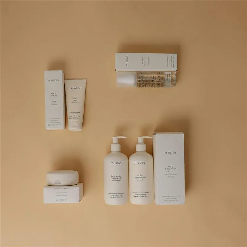 Mushie baby cream and various baby skincare products displayed on a soft beige background.