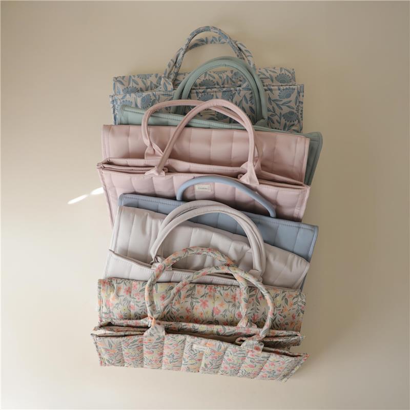 Mushie Baby Diaper Caddy in various colors, stacked neatly, showcasing its organizational compartments for newborn essentials.
