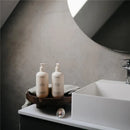 Mushie organic body lotion and shampoo on a wooden tray beside a modern sink in a stylish bathroom setting.