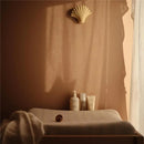 Mushie Baby Organic Body Lotion and related skincare products displayed on a soft surface in warm, natural light.