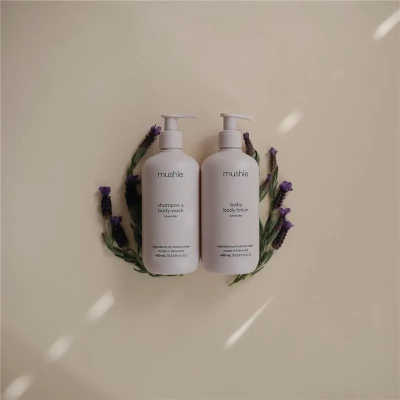 Mushie baby body lotion and shampoo & body wash in lavender, surrounded by lavender sprigs on a light background.
