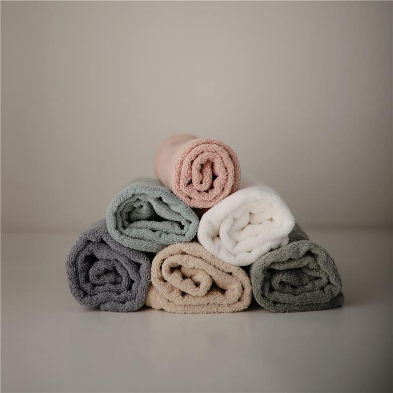 Hooded towels neatly rolled and stacked in soft colors: sea mist green, pink, white, beige, and gray.