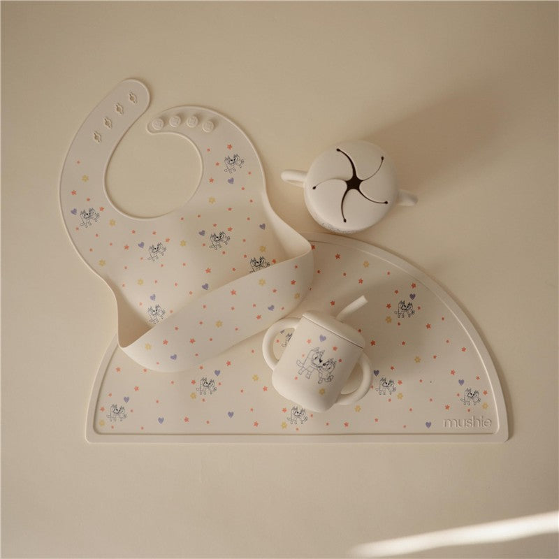 Silicone baby bib with a playful design and a matching cup, both featuring Bluey characters and colorful stars.