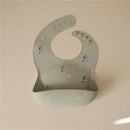 Silicone baby bib in sage green featuring Bluey character designs and a front pocket for food catchment.