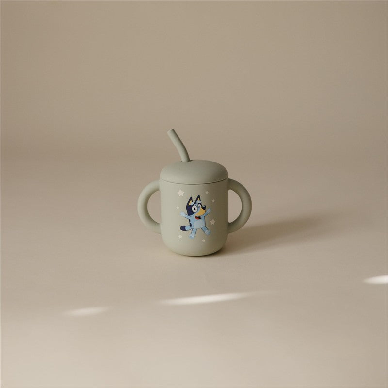 Mushie Silicone Training Cup in Bluey Sage with a blue cartoon dog design and a straw.