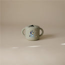 Bluey X Mushie snack cup in sage green featuring a playful Bluey design and two easy-to-grip handles.