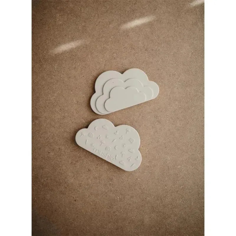 Mushie Cloud Teether in Shifting Sand color, featuring three layered clouds with textured designs on one side.