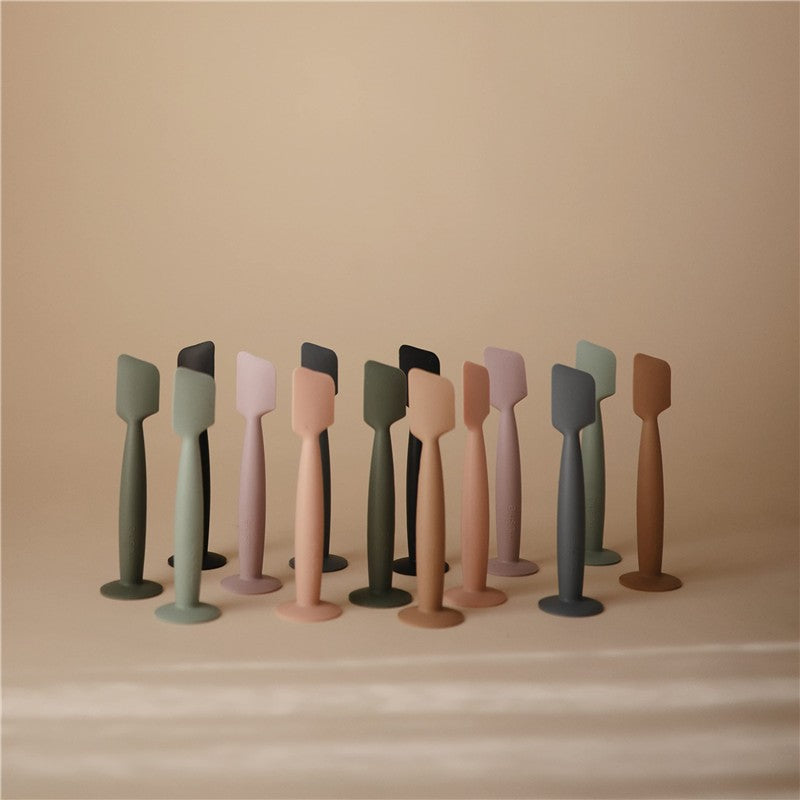 Mushie Diaper Cream Applicators in various pastel colors arranged against a neutral background, showcasing their sleek design.