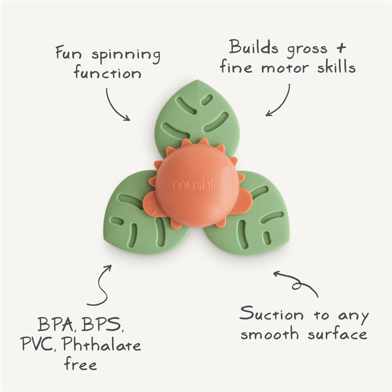 Mushie Dino Suction Spinner Toy in green and orange, designed for bath play, promoting motor skills, and adheres to smooth surfaces.