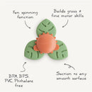 Mushie Dino Suction Spinner Toy in green and orange, designed for bath play, promoting motor skills, and adheres to smooth surfaces.