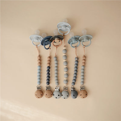 Mushie Eva Pacifier Clips in cloud colors, featuring silicone beads and wooden clips, designed to keep pacifiers secure.