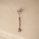 Mushie Eva pacifier clip in mauve with wood and silicone beads, designed to secure pacifiers and prevent loss.
