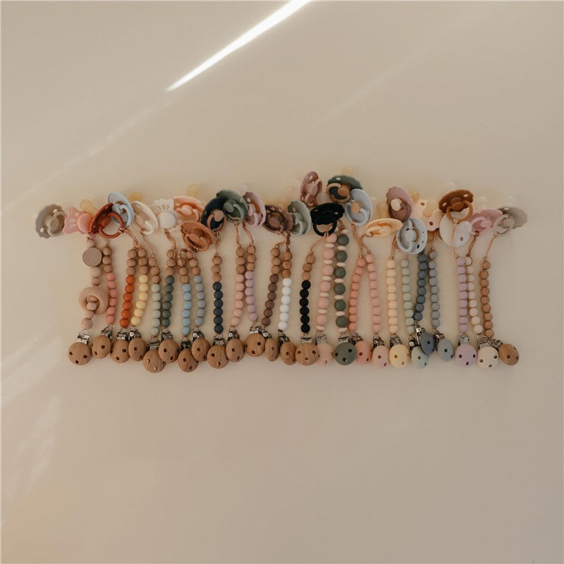 Mushie Eva pacifier clips in mauve and various colors, featuring silicone beads and clips for secure attachment.