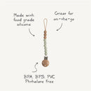 Mushie Eva Pacifier Clip in mauve, made with food-grade silicone, features beads and a wooden clip, labeled BPA, BPS, PVC free.