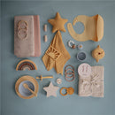 Mushie 2-Pack Finger Toothbrush in Shifting Sand and Blush colors, alongside various baby care accessories.
