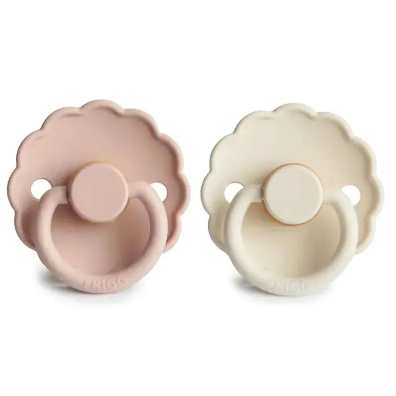 Two Mushie Frigg Daisy natural rubber baby pacifiers in blush and cream colors, suitable for ages 6 to 18 months.