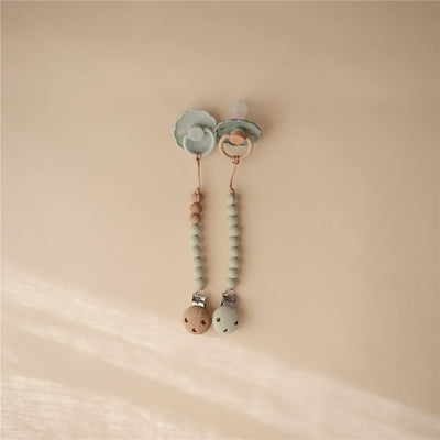 Silicone pacifier clip in sage color with wooden beads and metal clips, designed to secure pacifiers.