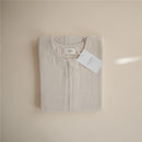 Mushie Muslin Sleep Bag in fog color, neatly folded with a tag displaying the brand name.
