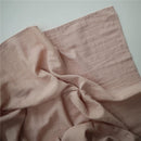 Muslin swaddle blanket in blush color, featuring a soft, textured fabric with a subtle grid pattern.