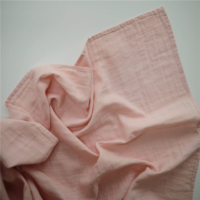 Mushie Organic Cotton Muslin Swaddle Blanket in a soft rose vanilla color, showing its lightweight, textured fabric.