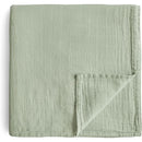 Mushie Organic Cotton Muslin Swaddle Blanket in sage green, featuring a soft, textured fabric with neatly sewn edges.