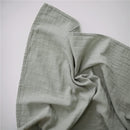 Organic cotton muslin swaddle blanket in sage color, crumpled fabric texture visible against a white background.