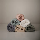 Stack of rolled towels in soft colors: light blue, dusty pink, white, beige, grey, and dark grey. Perfect for babies.