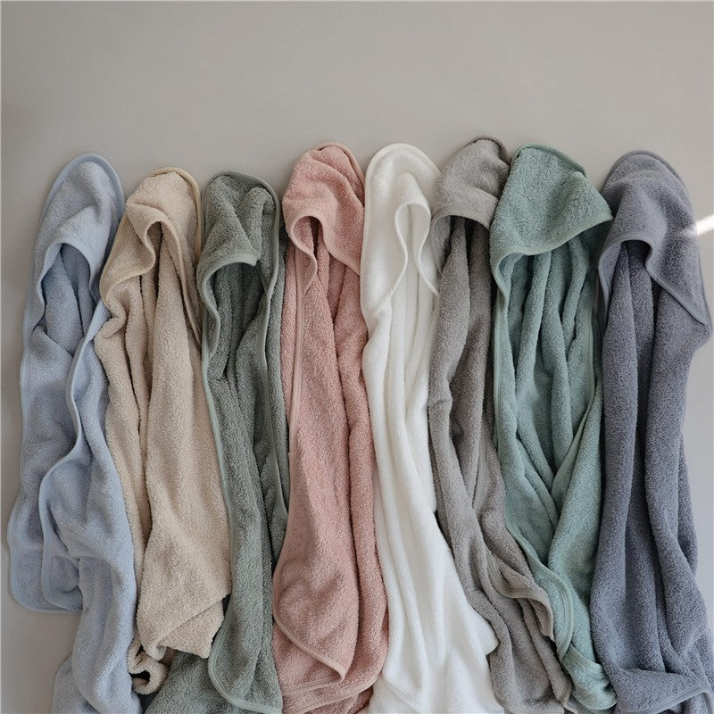 Soft, hooded towels in various colors including baby blue, stacked neatly, showcasing texture and design for baby bathing.