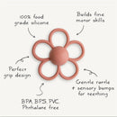Soft lilac Mushie Daisy Rattle Teether made of 100% food-grade silicone; features sensory bumps and a gentle rattle.