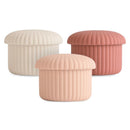 Silicone baby food containers in pink, blush, and cream, featuring a ribbed design and soft, rounded lids.