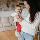 Silicone baby food container in pink held by a smiling woman with a child, both in a cozy indoor setting.