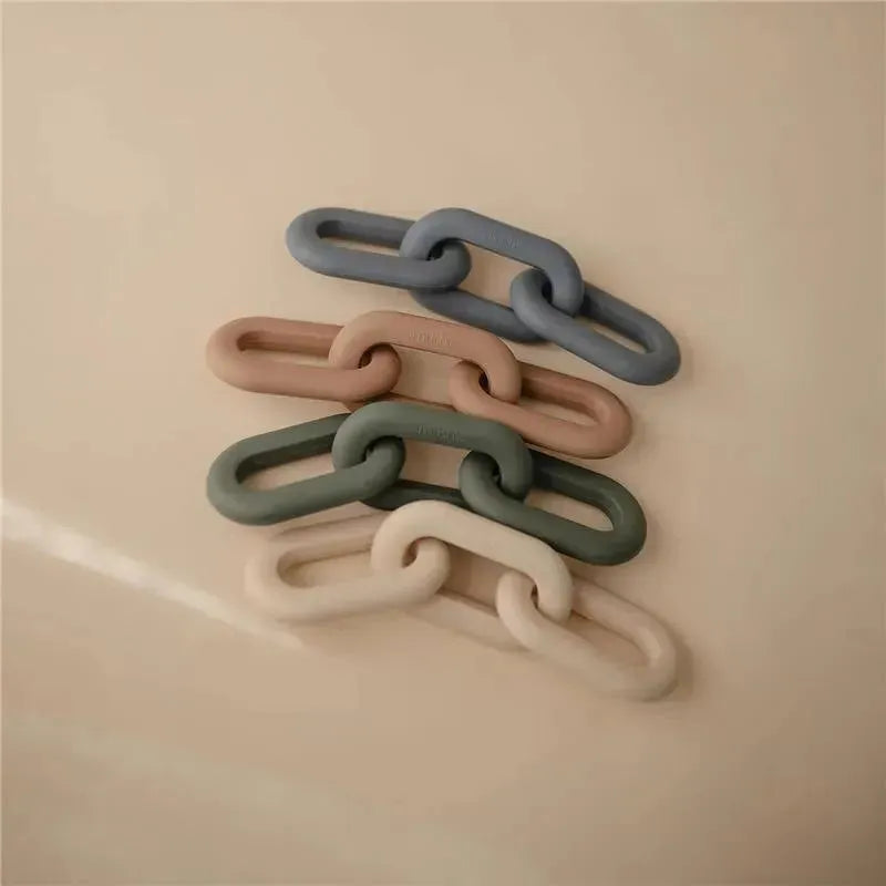 Silicone teether toy in varying pastel colors, stacked in a chain-like formation on a beige surface.